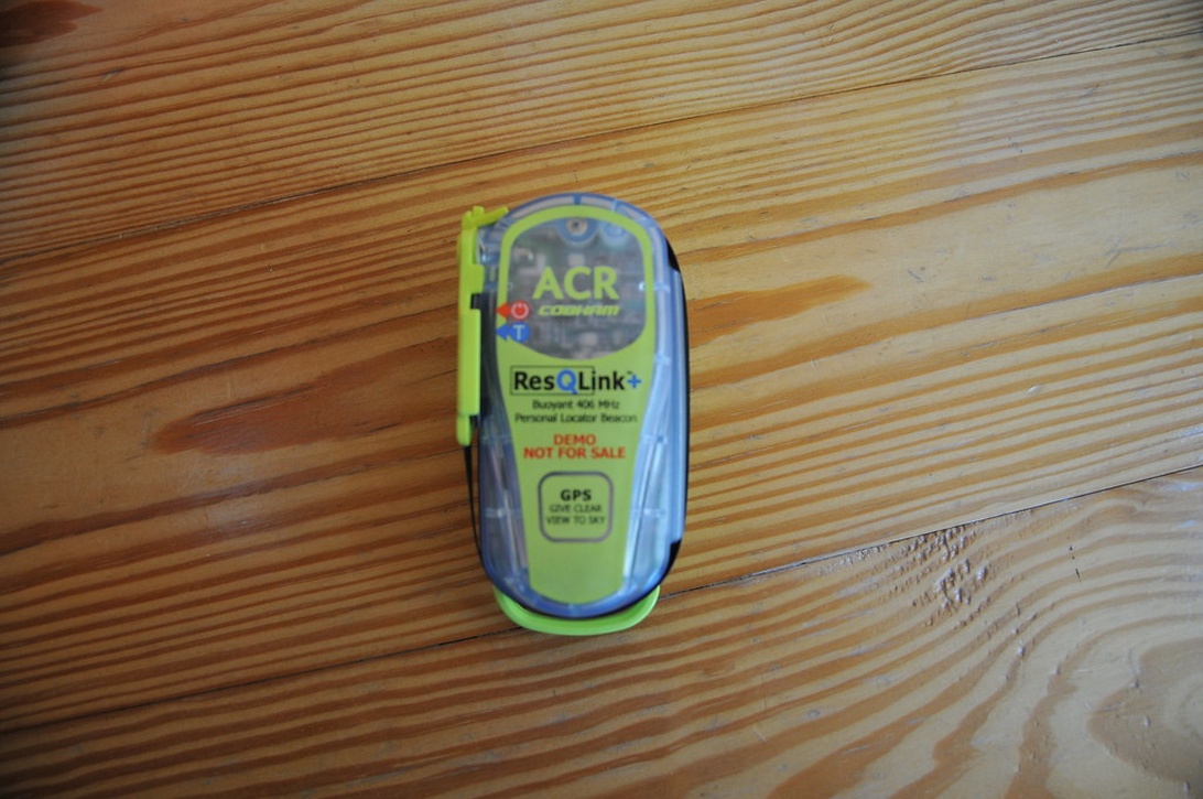 Ein gelb-transparentes ACR ResQLink+ Personal Locator Beacon (PLB) auf einer Holzoberfläche.