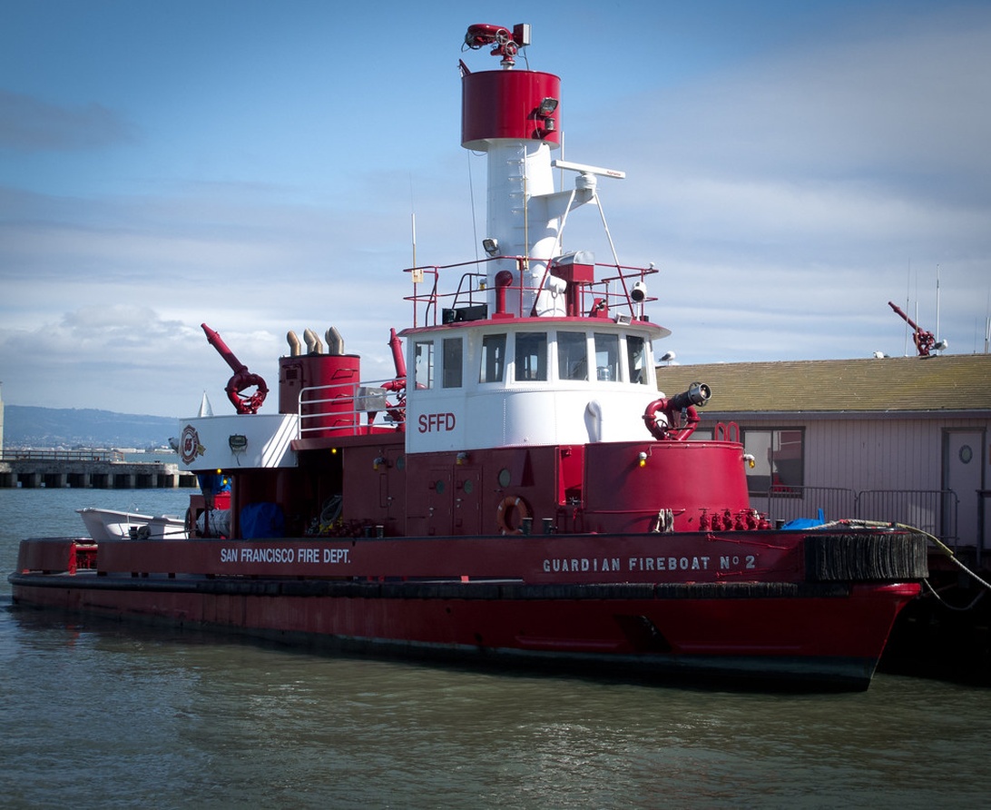 Ein rot-weißes Feuerlöschboot der Feuerwehr San Francisco liegt an einem Pier.